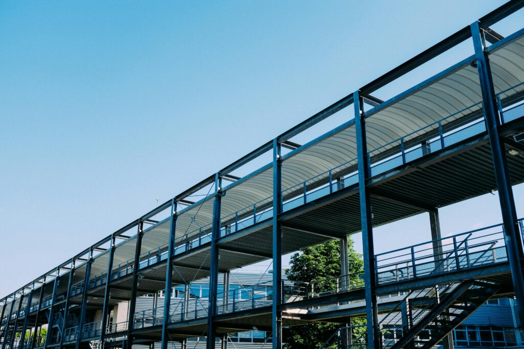 Low angle of metal stairway with passageways located at industrial workplace under cloudless sky